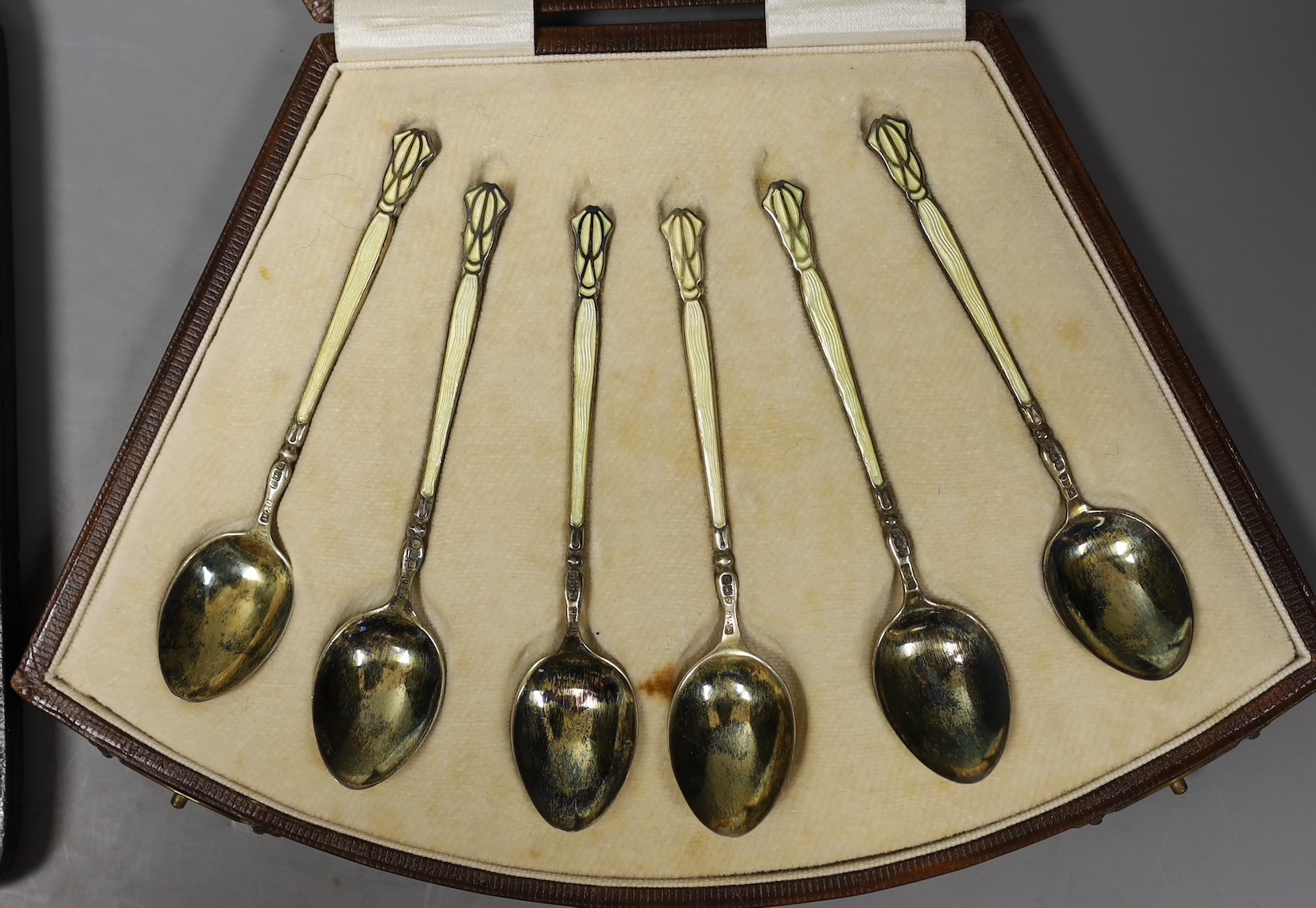 A cased set of six George V silver and enamel coffee spoons, Henry Clifford Davis, Birmingham, 1927, 95mm and a similar set of six silver coffee spoons.